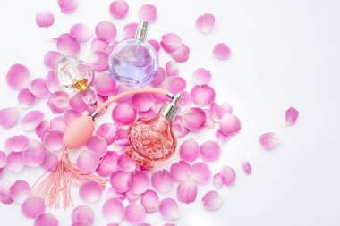 Beyaz arka planda çiçek yaprakları olan parfüm şişeleri. Parfüm, kozmetik, parfüm koleksiyonu..
