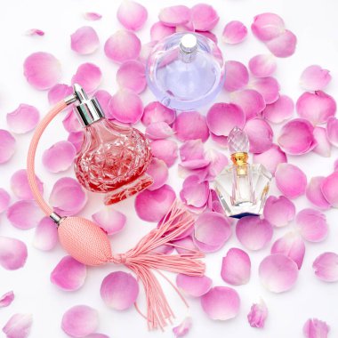 Beyaz arka planda çiçek yaprakları olan parfüm şişeleri. Parfüm, kozmetik, parfüm koleksiyonu..