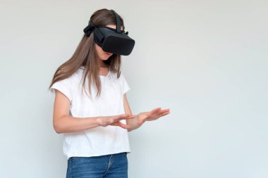 Sanal gerçeklik gözlüğü takan, gülümseyen olumlu bir kadın. Bağlantı, teknoloji, yeni nesil, ilerleme kavramı. Sanal gerçeklikte nesnelere dokunmaya çalışan bir kız. Stüdyo çekimi gri üzerine.