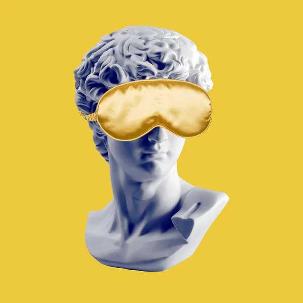 Statue in gold sleep mask. Gypsum statue of David head. Plaster copy of David\'s head in sleeping mask. Creative, sleep and relax concept. Minimal concept art. Last or blind judgment. Toned picture