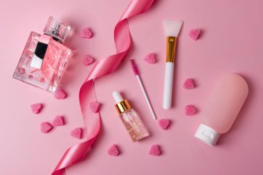 Yaşlanma önleyici serum, kolajen ve peptid, şişede damla. Cilt bakımı esansı cam şişeler, parfüm, plastik kapta vücut losyonu ve pembe arka planda kağıt alışveriş torbası. Kozmetik