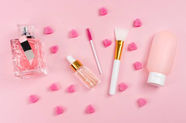 Yaşlanma önleyici serum, kolajen ve peptid, şişede damla. Cilt bakımı esansı cam şişeler, parfüm, plastik kapta vücut losyonu ve pembe arka planda kağıt alışveriş torbası. Kozmetik