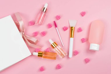 Yaşlanma önleyici serum, kolajen ve peptid damlatan cam şişede. Kağıt hediyeli cam şişeler ya da pembe arka planda alışveriş torbası. Cilt için vitamin. Kozmetik kavramı