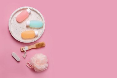 Şampuan, saç kremi ve mermer tepside bez bulunan duş jeli için renkli plastik kaplar. Spa için kozmetik ürünler ve pembe arka planda banyo aksesuarları. Güzellik, seyahat konsepti, düz yatak.