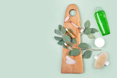 Yüz silindiri, gerekli yağlar, kozmetik serumlar, masaj fırçası ve doğal okaliptüs yapraklı vücut losyonu. Güzellik malzemeleri, masaj aletleri, yüz bakımı, güzellik tedavi konsepti. Düz yatıyordu