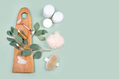 Yüz silindiri, gerekli yağlar, kozmetik serumlar, masaj fırçası ve doğal okaliptüs yapraklı mumlar. Güzellik malzemeleri, masaj aletleri, yüz bakımı, güzellik tedavi konsepti. Düz yatıyordu