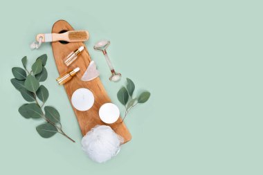 Yüz silindiri, gerekli yağlar, kozmetik serumlar, masaj fırçası ve doğal okaliptüs yapraklı mumlar. Güzellik malzemeleri, masaj aletleri, yüz bakımı, güzellik tedavi konsepti. Düz yatıyordu