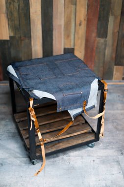 Masasında deri kayışlar olan Denim barmen önlüğü. Boş alanı olan ahşap arkaplan