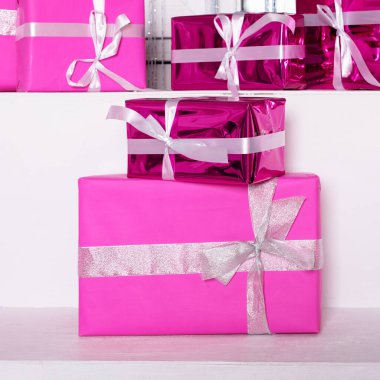 Beyaz masa üzerinde kurdele olan pembe kutlama kutuları yığını. Kış tatili kavramı