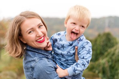 Mutlu anne eğleniyor. Sonbahar parkında havadan çocuk kusuyor.