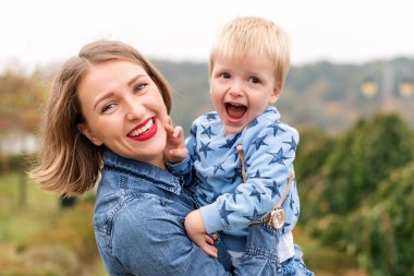Mutlu anne eğleniyor. Sonbahar parkında havadan çocuk kusuyor.