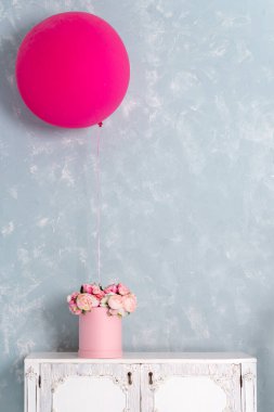 Yuvarlak lüks hediye kutusunda çiçekler ve çekmecelerin üzerinde büyük pembe bir balon. Kağıt kutuda pembe ve beyaz şakayık demeti. İç dekorasyon pastel renklerde. Metin için boş telif alanı