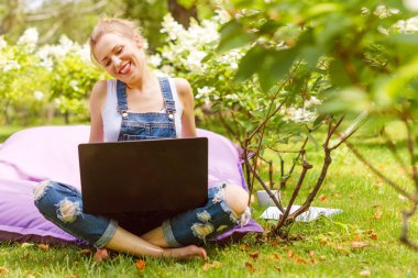 Bahçede çalışan mutlu bir serbest yazar. Yazmak, internette sörf yapmak, dizüstü bilgisayar kullanmak. Genç bir kadın park alanında rahatlıyor ve eğleniyor. Uzaklık eğitimi, serbest çalışma kavramı