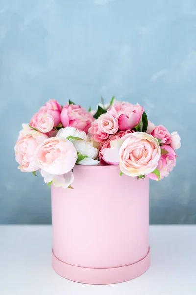 Flowers in round luxury present box. Bouquet of pink and white peonies in paper box. Mock-up of hat box of flowers with free copyspace for text. Interior decoration in in pastel colors