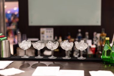 Tezgahta buzlu kokteyl bardakları barmeni bekliyor.