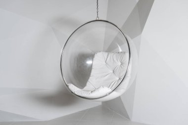 Geometrik şekilli beyaz bir duvara karşı şeffaf cam sandalye