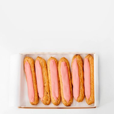 Beyaz arka planda altı tane taze pembe kek olan karton kutuyu aç. Üst görünüm, metin için boşluk. Sağlıksız ya da diyet konsepti