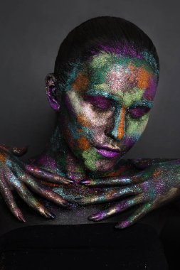 Siyah boyalı ve renkli tozlu genç sanatçı kadın. Parlak koyu renk makyaj. Uzay ve yıldızlar teması üzerine yaratıcı vücut sanatı. Vücut boyama projesi: sanat, güzellik, moda