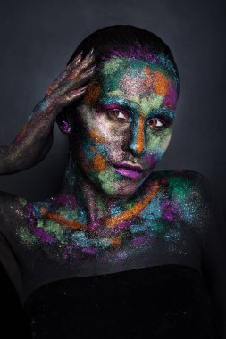 Siyah boyalı ve renkli tozlu genç sanatçı kadın. Parlak koyu renk makyaj. Uzay ve yıldızlar teması üzerine yaratıcı vücut sanatı. Vücut boyama projesi: sanat, güzellik, moda
