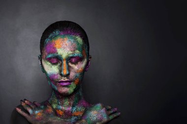 Siyah boyalı ve renkli tozlu genç sanatçı kadın. Parlak koyu renk makyaj. Uzay ve yıldızlar teması üzerine yaratıcı vücut sanatı. Vücut boyama projesi: sanat, güzellik, moda