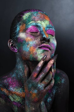 Siyah boyalı ve renkli tozlu genç sanatçı kadın. Parlak koyu renk makyaj. Uzay ve yıldızlar teması üzerine yaratıcı vücut sanatı. Vücut boyama projesi: sanat, güzellik, moda
