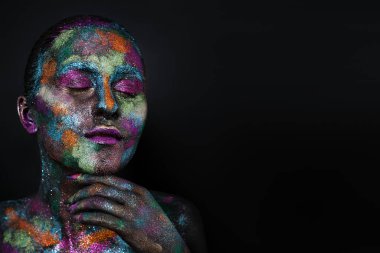 Siyah boyalı ve renkli tozlu genç sanatçı kadın. Parlak koyu renk makyaj. Uzay ve yıldızlar teması üzerine yaratıcı vücut sanatı. Vücut boyama projesi: sanat, güzellik, moda