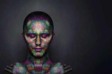 Siyah boyalı ve renkli tozlu genç sanatçı kadın. Parlak koyu renk makyaj. Uzay ve yıldızlar teması üzerine yaratıcı vücut sanatı. Vücut boyama projesi: sanat, güzellik, moda