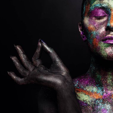 Siyah boyalı ve renkli tozlu genç sanatçı kadın. Parlak koyu renk makyaj. Uzay ve yıldızlar teması üzerine yaratıcı vücut sanatı. Vücut boyama projesi: sanat, güzellik, moda