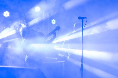 Gitarist silueti konser sahnesinde performans sergiliyor. Soyut müzik geçmişi. Gitaristli müzik grubu. Gitar çalmak ve konser konsepti. Canlı müzik, festival geçmişi. Sahnede Aygıt