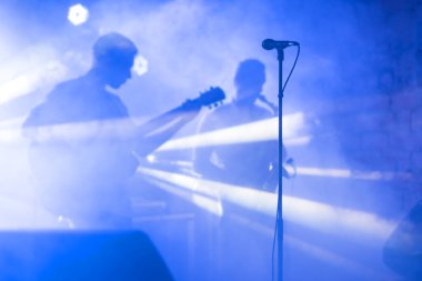 Gitarist silueti konser sahnesinde performans sergiliyor. Soyut müzik geçmişi. Gitaristli müzik grubu. Gitar çalmak ve konser konsepti. Canlı müzik, festival geçmişi. Sahnede Aygıt