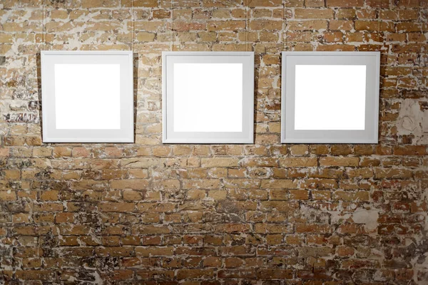 Three empty frames on light brick wall. Blank space posters or art frame waiting to be filled. Square Black Frame Mock-Up.