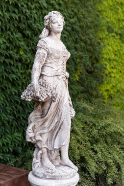 Parkta bir sepet üzümlü mermer heykel kadın.