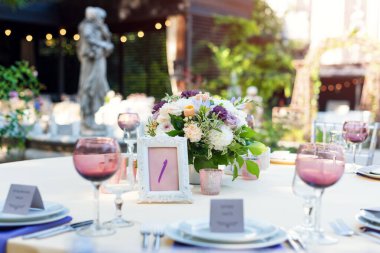 Tatiller ve düğün yemeği için çiçek masası süslemeleri. Açık hava restoranında tatil, etkinlik, parti veya düğün resepsiyonu için masa hazır.