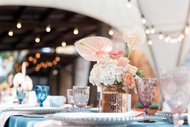 Tatiller ve düğün yemeği için çiçek masası süslemeleri. Açık hava restoranında tatil, etkinlik, parti veya düğün resepsiyonu için masa hazır.