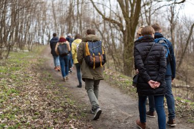 Bahar ormanlarında sırtlarında sırt çantalarıyla dolaşan bir grup arkadaş. Sırt çantalı gezginler ormanda yürüyüş yapıyor. Macera, seyahat, turizm, aktif dinlenme, yürüyüş ve insanların arkadaşlık konsepti