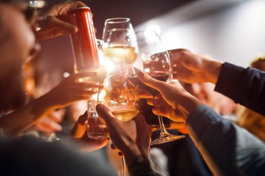 Yemek masasının üstünde kadeh tokuşturan neşeli arkadaşlar. Alkol ve tost, parti ve kutlama teması. Olayın için tebrikler.