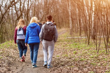 Bahar ormanlarında sırtlarında sırt çantalarıyla dolaşan bir grup arkadaş. Sırt çantalı gezginler ormanda yürüyüş yapıyor. Macera, seyahat, turizm, aktif dinlenme, yürüyüş ve insanların arkadaşlık konsepti