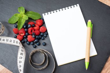 Yabanmersini, ahududu, nane, mezura, not ve notlar yazmak için not defteri, spor, diyet, zayıflama, detoks, sağlıklı yaşam tarzları ve beslenme konsepti. Metin için boşluk oluştur