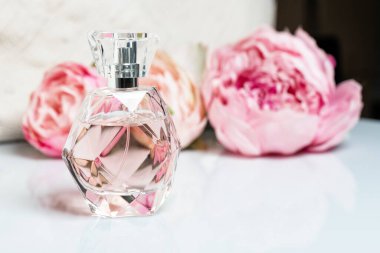 Arka planda çiçekler olan parfüm şişesi. Parfüm, kozmetik, parfüm koleksiyonu..