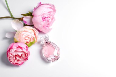 Açık arkaplanda çiçekler olan pembe parfüm şişesi. Parfüm, kozmetik, parfüm koleksiyonu. Metin için boş alan