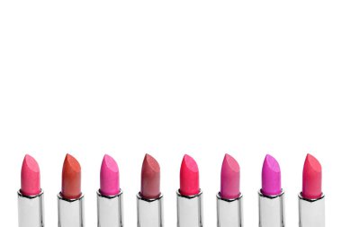 Beyaz arkaplanda izole edilmiş sıraya dizilmiş renkli ruj seti. Bir sıra kırmızı, pembe ve şarap ruju. Yazmak için boş yeri var..