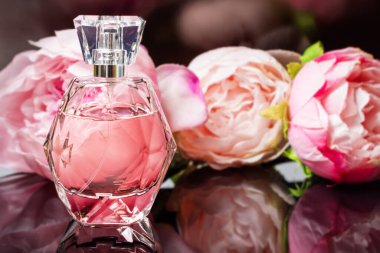 Arka planda çiçekler olan parfüm şişesi. Parfüm, kozmetik, parfüm koleksiyonu..