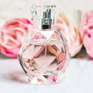 Arka planda çiçekler olan parfüm şişesi. Parfüm, kozmetik, parfüm koleksiyonu..