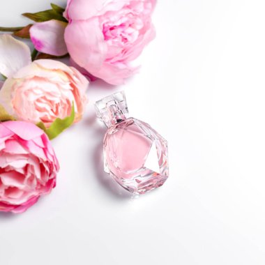 Açık arkaplanda çiçekler olan pembe parfüm şişesi. Parfüm, kozmetik, parfüm koleksiyonu. Metin için boş alan