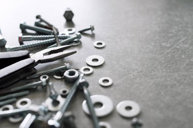 İnşaat aletleri. Beton arka planda pense, vida, somun ve cıvatalar var. Tamir, ev geliştirme konsepti. Metin için boş alan, üst görünüm, düz uzanma