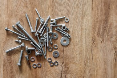 İnşaat aletleri. Tahta arka plandaki vidalar, somunlar ve cıvatalar. Tamir, ev geliştirme konsepti. Metin için boş alan, üst görünüm, düz uzanma