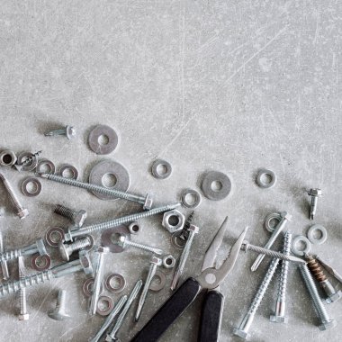 İnşaat aletleri. Beton arka planda pense, vida, somun ve cıvatalar var. Tamir, ev geliştirme konsepti. Metin için boş alan, üst görünüm, düz uzanma