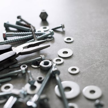 İnşaat aletleri. Beton arka planda pense, vida, somun ve cıvatalar var. Tamir, ev geliştirme konsepti. Metin için boş alan, üst görünüm, düz uzanma