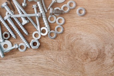 İnşaat aletleri. Tahta arka plandaki vidalar, somunlar ve cıvatalar. Tamir, ev geliştirme konsepti. Metin için boş alan, üst görünüm, düz uzanma