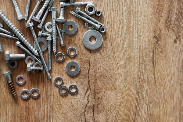 Construction tools. The screws, nuts and bolts on wooden background. Repair, home improvement concept. Free space for text, top view, flat lay